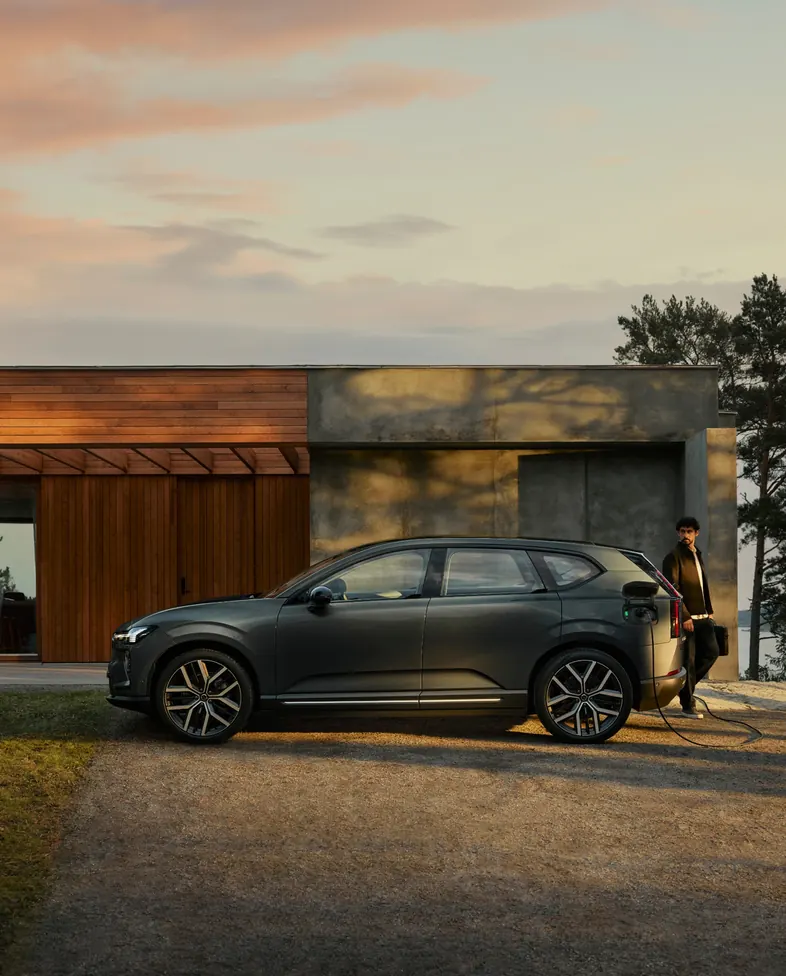 Volvo estacionado ao entardecer em frente a uma casa entre árvores